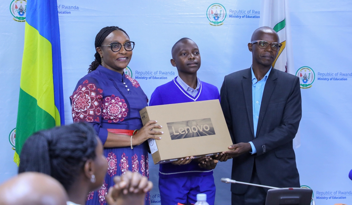 Minister Valentine Uwamariya hands over a laptop to Forever Hyacente Isezerano  the top performer in  national examinations result of Primary school from St Andre in Muhanga district. Dan Nsengiyumva.