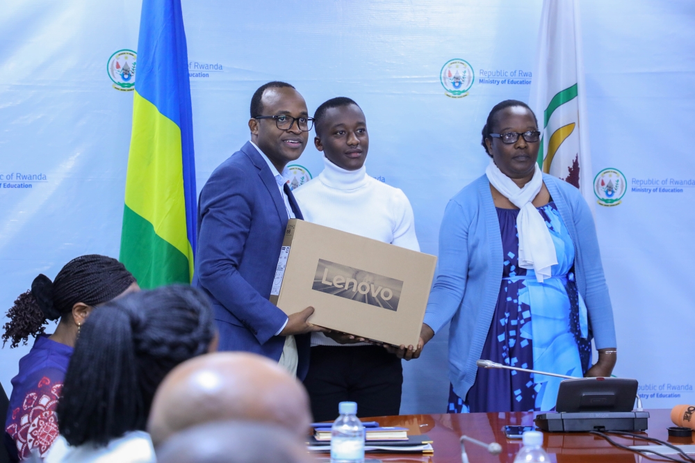 State minister for Primary and Secondary Education, Gaspard Twagirayezu, hands over a laptop to Albert Ntwali Manzi (from Académie de la Salle, Gicumbi), the best performer in O’Level, in Kigali on September 27. Photo: Dan Nsengiyumva.