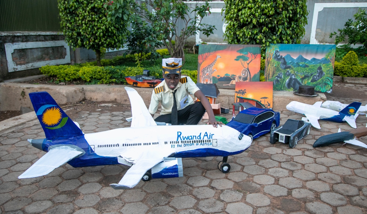 Joshua Kirungi Mugisha, 13-year-old, poses for a photo with some of his craft products like cars, planes, crafted animals, movie superheroes. Photo: Willy Mucyo.