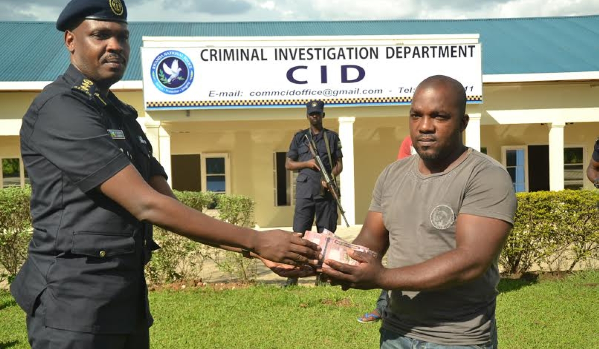 Rwanda National Police&#039;s  Chief Supt. Peter Karake hands over 11 million Ugandan shillings to Milindi Kamili, a Rwandan businessman in Uganda that was recovered from a suspected thief, who had crossed into Rwanda on December 3, 2015. The National Police is set to regain powers to conduct criminal investigations. / Courtesy