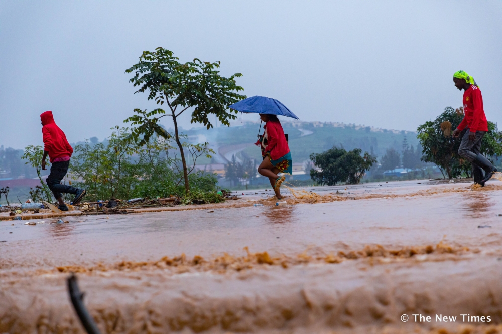 People wade through a flooded street in Kigali. METEO alerted tha some parts of Southern and Eastern Provinces have experienced rainfall deficit in the previous period .File