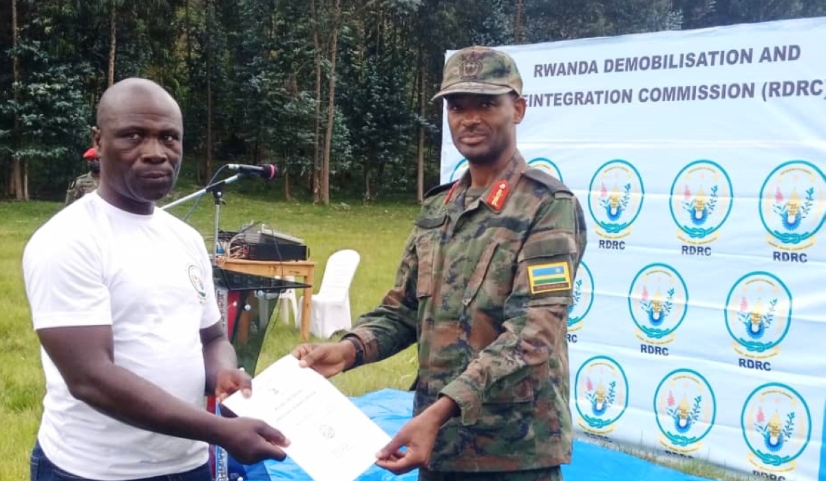 Lt Gen Mubarakh Muganga, Army Chief of Staff hands over a certificate to one of the 57 former combatants of armed groups based in Eastern DR Congo, who completed a training in entrepreneurship and civic education, at Mutobo in Musanze District. Photos by Germain Nsanzimana

