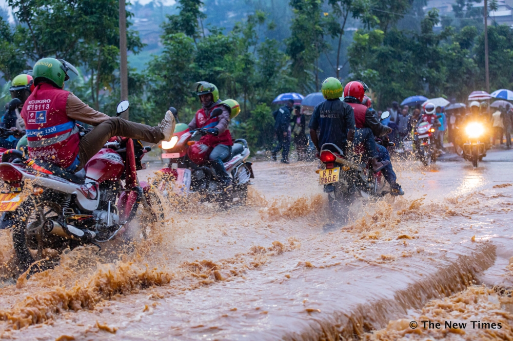 Taxi-moto operators wade through a flooded street in Kigali. Following the heavy rains that killed a motorist and two more people, on November 16 ,the City of Kigali has warned residents not drive during heavy rains. File