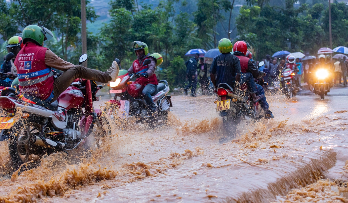 Taxi-moto operators wade through a flooded street in Kigali. Following the heavy rains that killed a motorist and two more people, on November 16 ,the City of Kigali has warned residents not drive during heavy rains. File