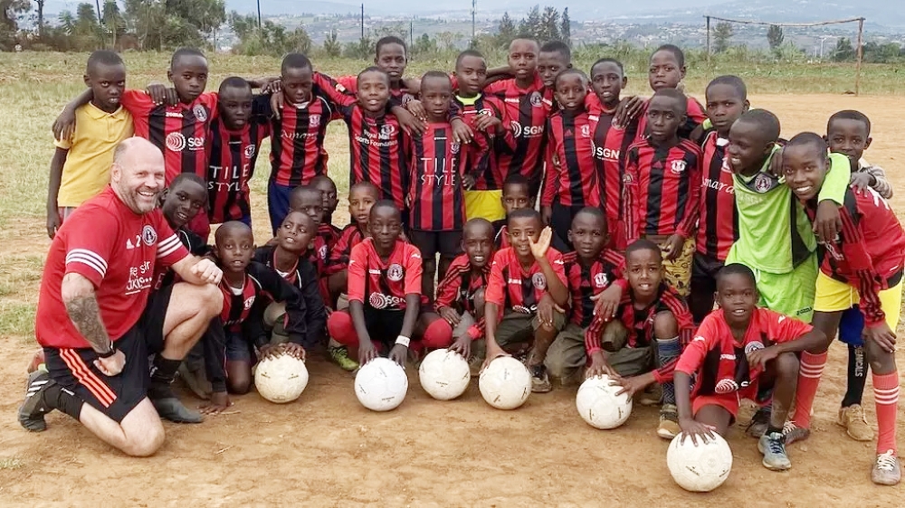 Children pose for a group photo after receiving new jersey and balls donated by by Scottish football coaches. Courtesy