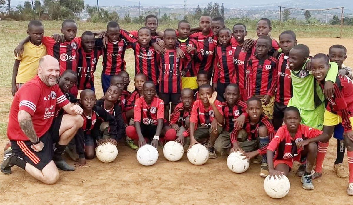 Children pose for a group photo after receiving new jersey and balls donated by by Scottish football coaches. Courtesy