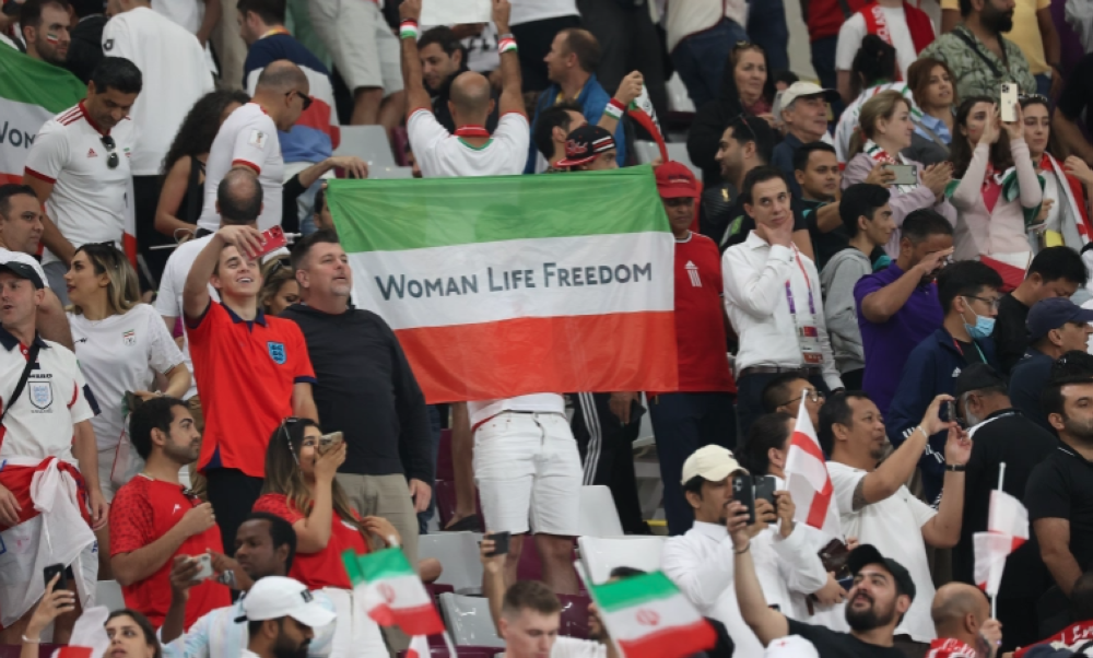 A man holds a &#039;Woman Life Freedom&#039; Iranian flag. [Showkat Shafi/Al Jazeera]