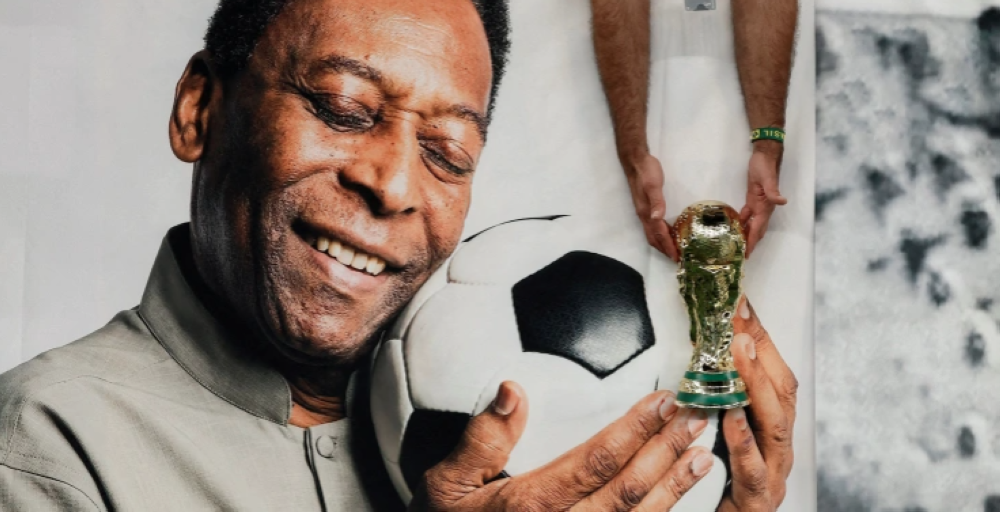 A Brazil fan holds a replica World Cup trophy in front of a banner of legendary Brazilian player Pele before the Cameroon vs Brazil match at Lusail Stadium, Qatar, on December 2, 2022 [File: Benoit Tessier/Reuters]