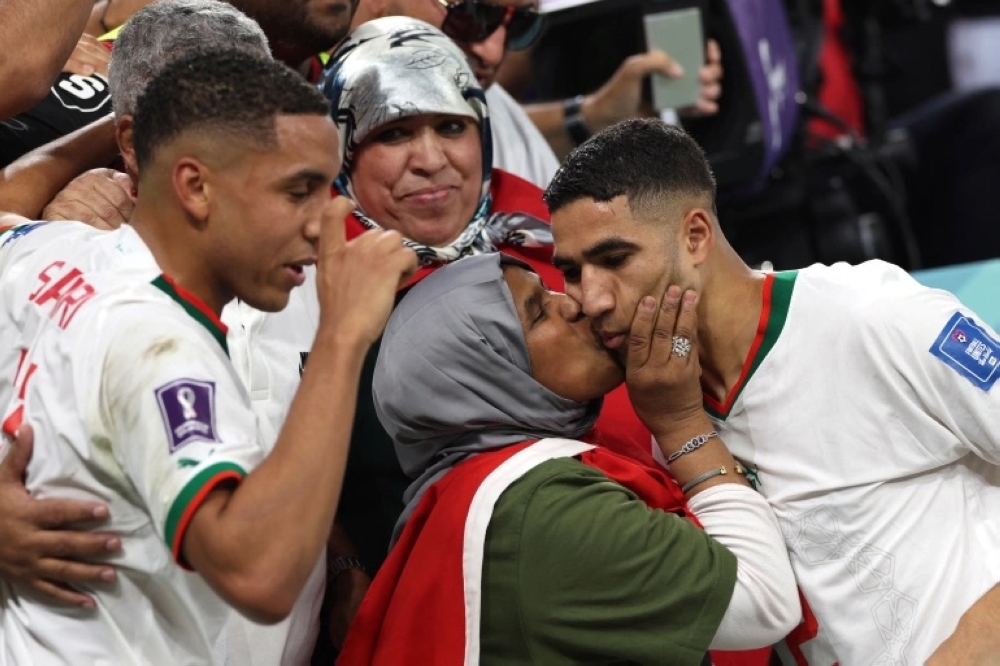 Hakimi, right, is embraced by his mother at the end of the World Cup match between Belgium and Morocco [Fadel Senna / AFP]