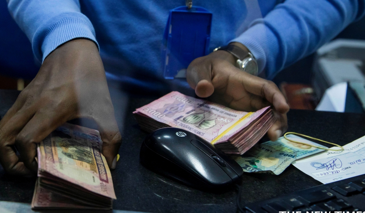 A bank teller counts money while serving customers at Bank of Kigali head office. File