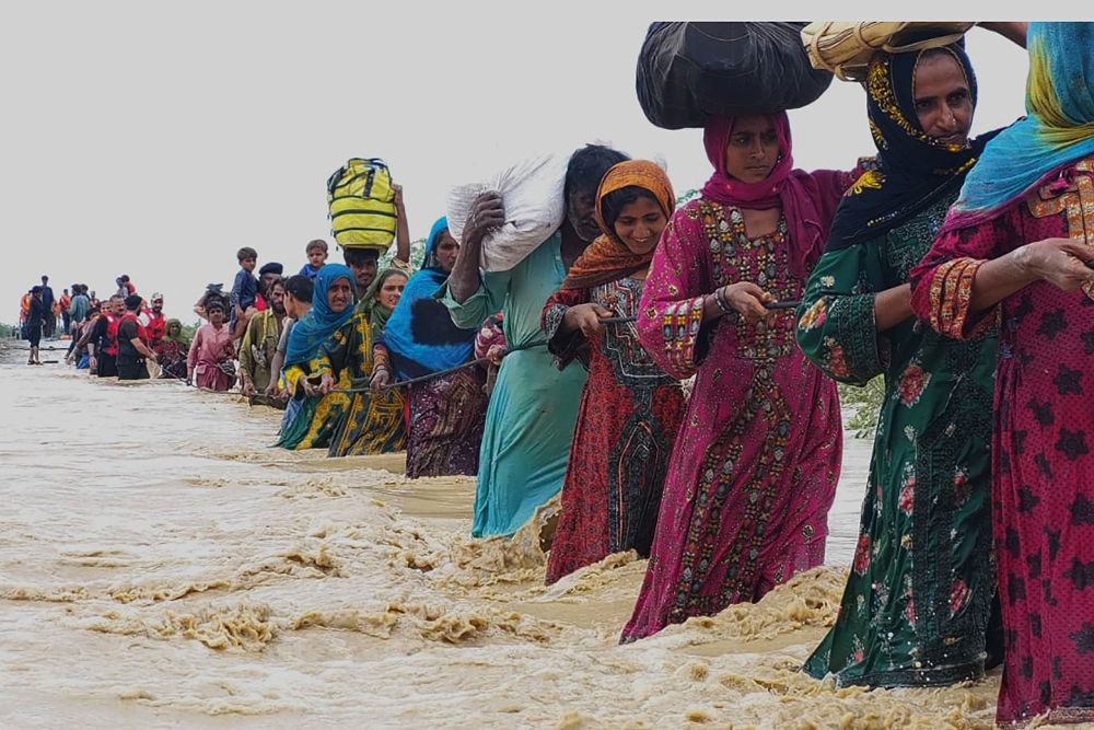 Pakistanis wade through a flooded area that was strongly affected by floods in Pakistan that left many people homeless. Internet