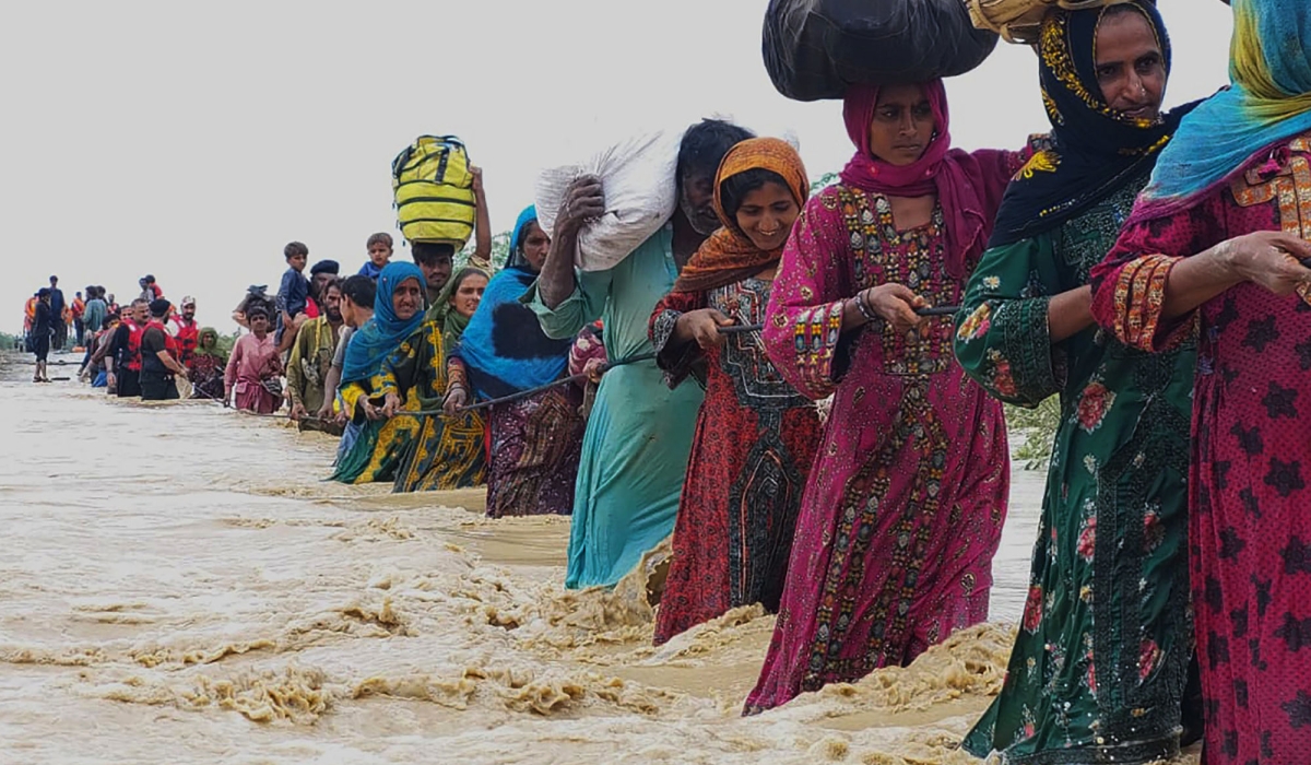 Pakistanis wade through a flooded area that was strongly affected by floods in Pakistan that left many people homeless. Internet