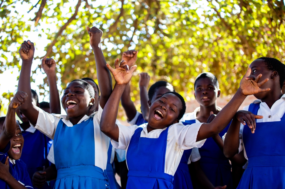 (Front left to right) Sharifa, 13, Florence, 14, and Grace, 14, cheer alongside their fellow classmates outside their school in Salima, Malawi to celebrate that trachoma has been eliminated in the coun