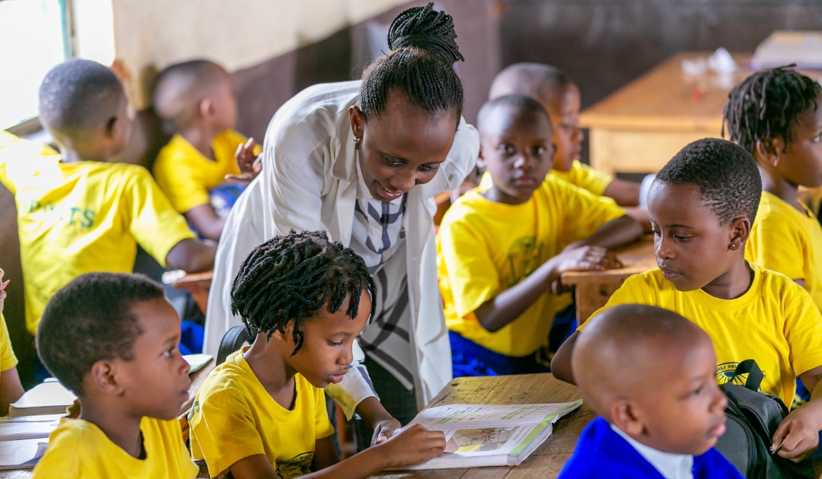 A primary school teacher helps pupils during a class at Groupe Scolaire Camp Kigali in 2019. The government plans to raise spending by Rwf106.4 billion in revised budget to cater for school feeding for all students, teachers’ salaries and fertiliser. File 