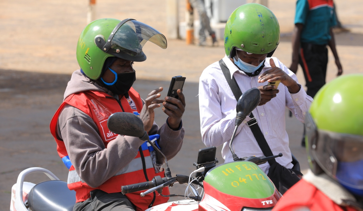 A moto taxi user pays the transport fee via Mobile money in Kigali. RURA re-introduces taxi-moto metres. File