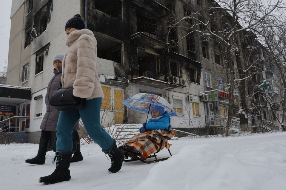 People walk past a damaged building in Mariupol, February 18. Photo by Victor/Xinhua