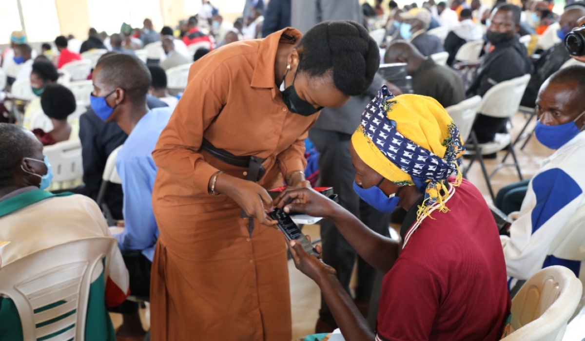 Minister of ICT and Innovation Paula Ingabire helps a resident to switch on a smartphone in Bugesera District. File
