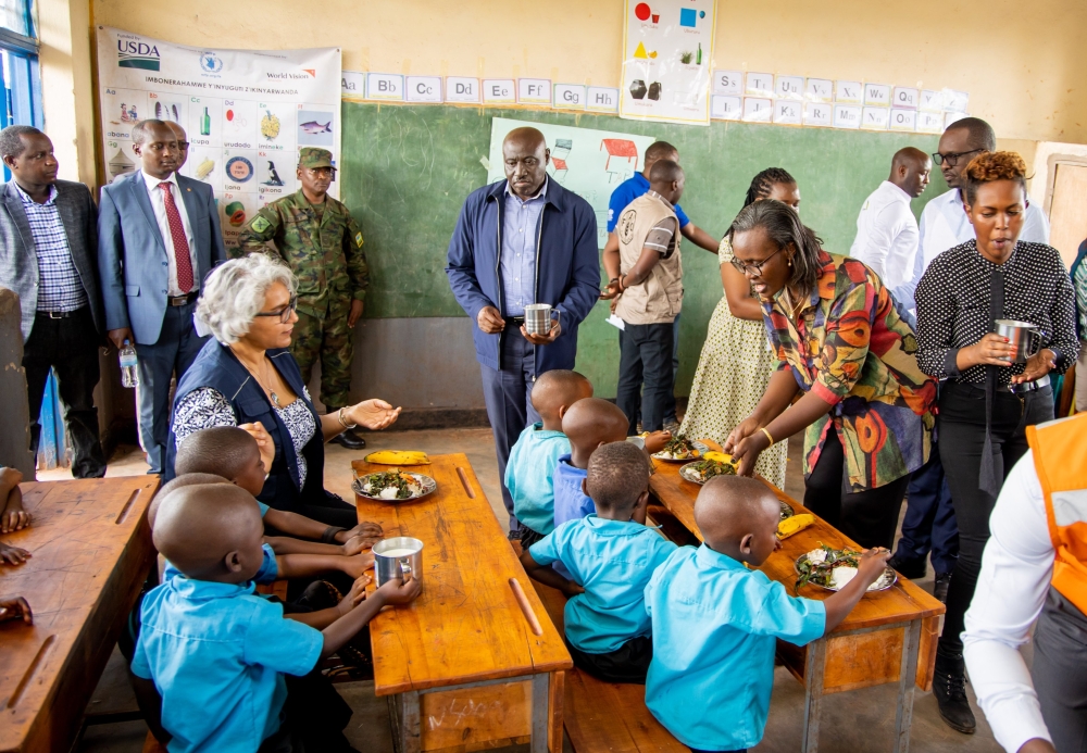 Rose Baguma, Director General of Education Policy and Analysis at the Ministry of Education, CG Emmanuel Gasana, Governor of Eastern Province together with other officials serving meal to children