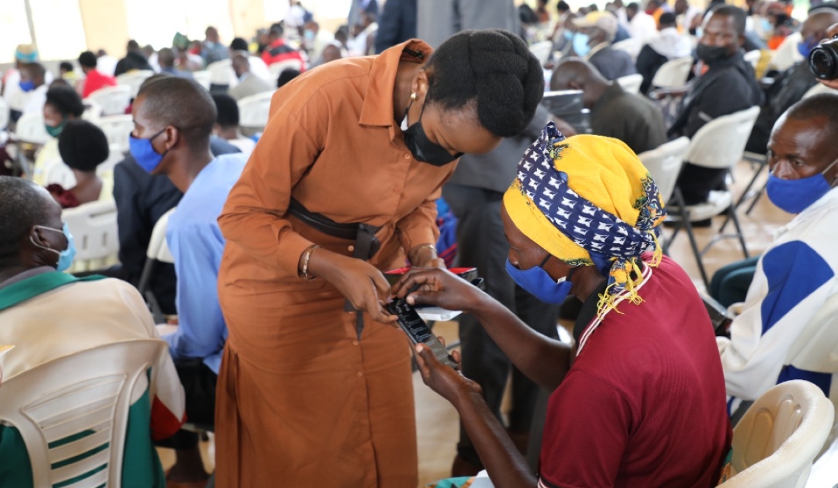 Minister of ICT and Innovation Paula Ingabire helps a resident to switch on a smartphone in Bugesera District. File 