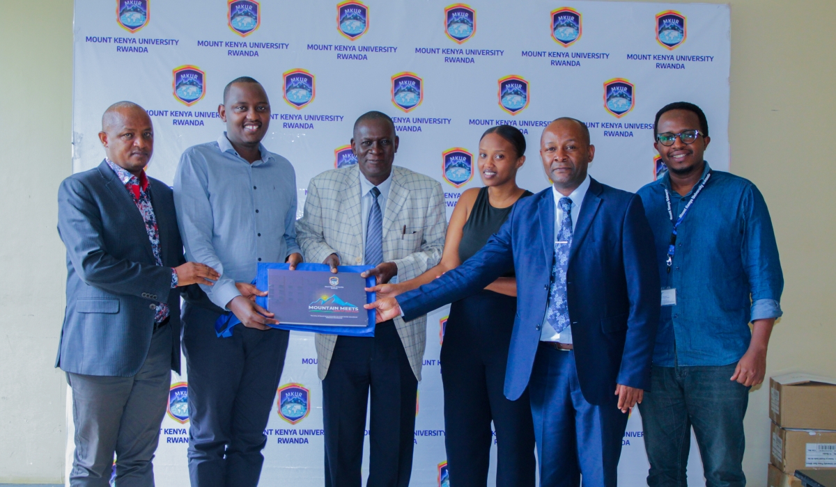 The Vice-Chancellor Designate, Prof Edwin Odhuno (3rd from left) hands over " Mountain Meets land of 1,000 hills" memoir to  Elijah Nyemina as members of staff of MKUR and a student, Mutoniwabo Benitha of School of Journalism and Mass Media looks on. Courtesy 