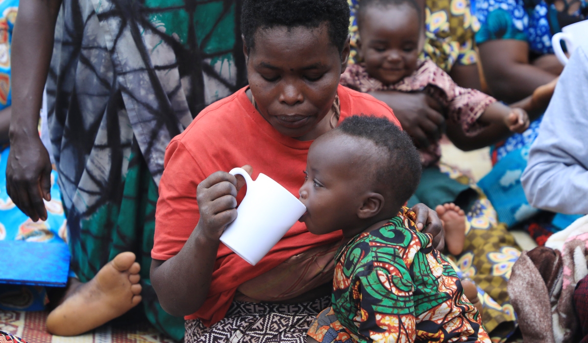 A woman helps her baby to take porridge in Nyamasheke District.Activists are seeking to reduce the burden of unpaid care and domestic work on women by getting more men to take an equal share .Photo by Craish Bahizi