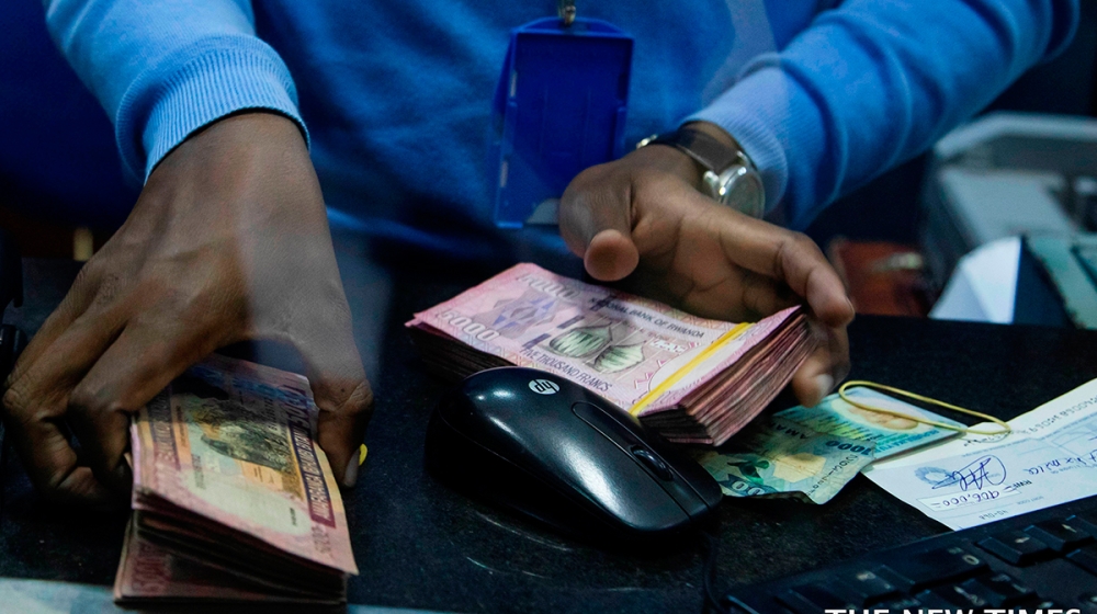 A bank teller counts money while serving customers at Bank of Kigali .The National Bank of Rwanda  announced key economic developments in 2022 through its Monetary Policy Committee and Financial Stability Statement.