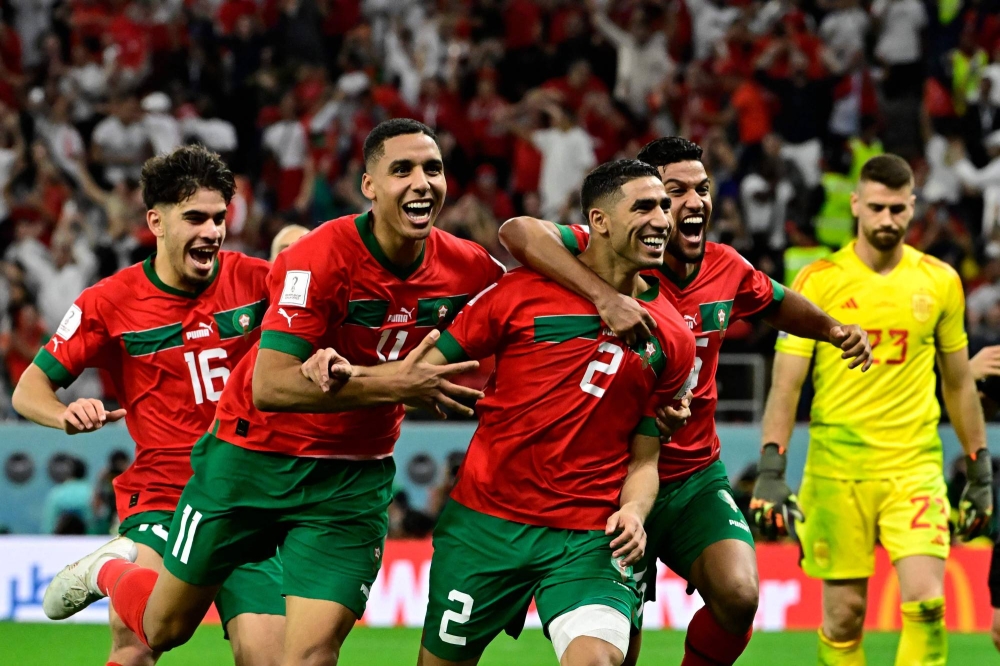 TOPSHOT - Morocco&#039;s defender #02 Achraf Hakimi (2nd R) celebrates with teammates after converting the last penalty during the penalty shoot-out to win the Qatar 2022 World Cup round of 16 football match between Morocco and Spain at the Education City Stadium in Al-Rayyan, west of Doha on December 6, 2022. (Photo by JAVIER SORIANO / AFP)