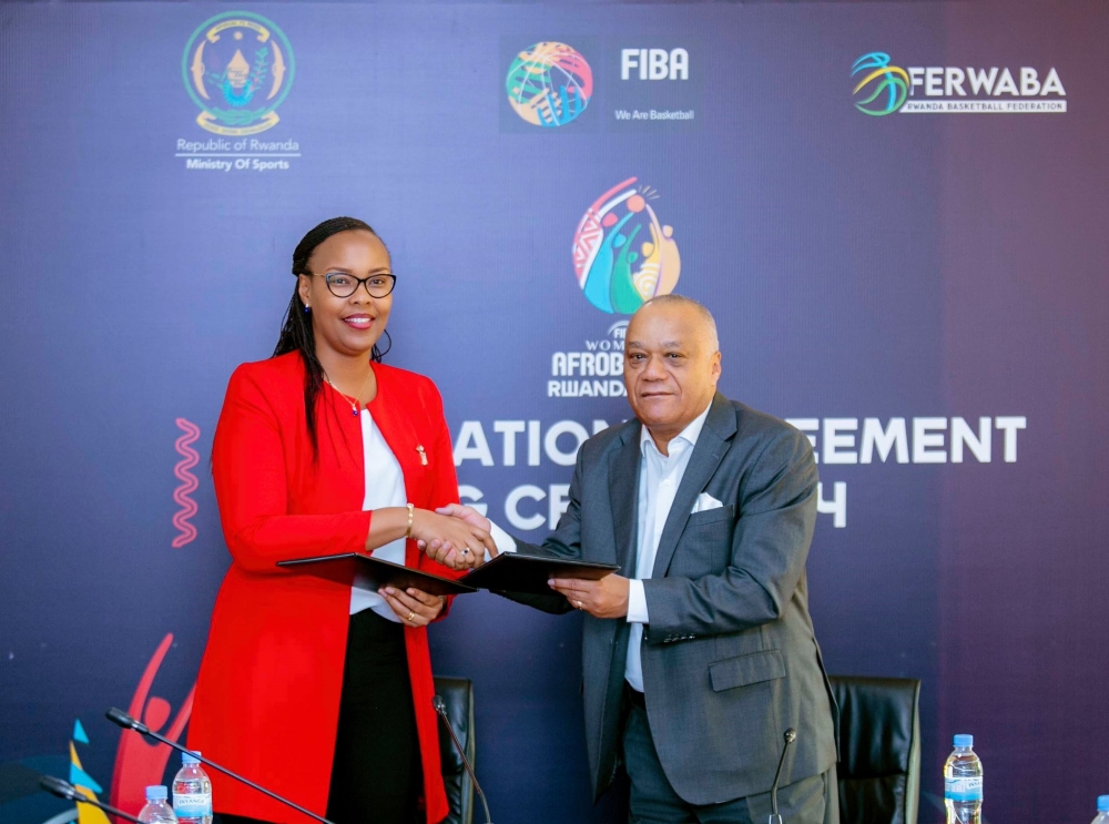 Sports Minister Aurore Mimosa Munyangaju and Alphonse Bilé, the FIBA Africa Regional Director exchange documents during the  signing ceremony  in Kigali on Thursday, May 25. Courtesy