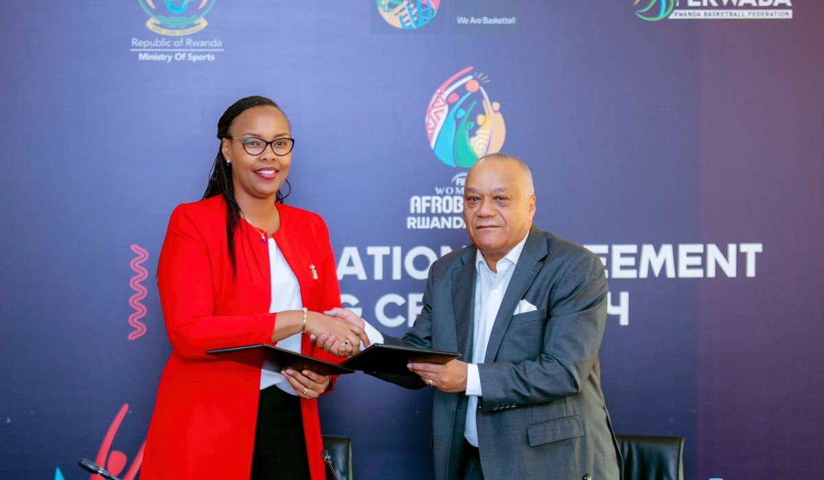 Sports Minister Aurore Mimosa Munyangaju and Alphonse Bilé, the FIBA Africa Regional Director exchange documents during the  signing ceremony  in Kigali on Thursday, May 25. Courtesy