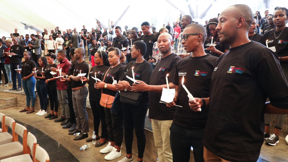 Mourners hold candles while observing a moment of silence to pay tribute to victims of the Genocide Against the Tutsi during a Commemoration event at Kigali Genocide Memorial