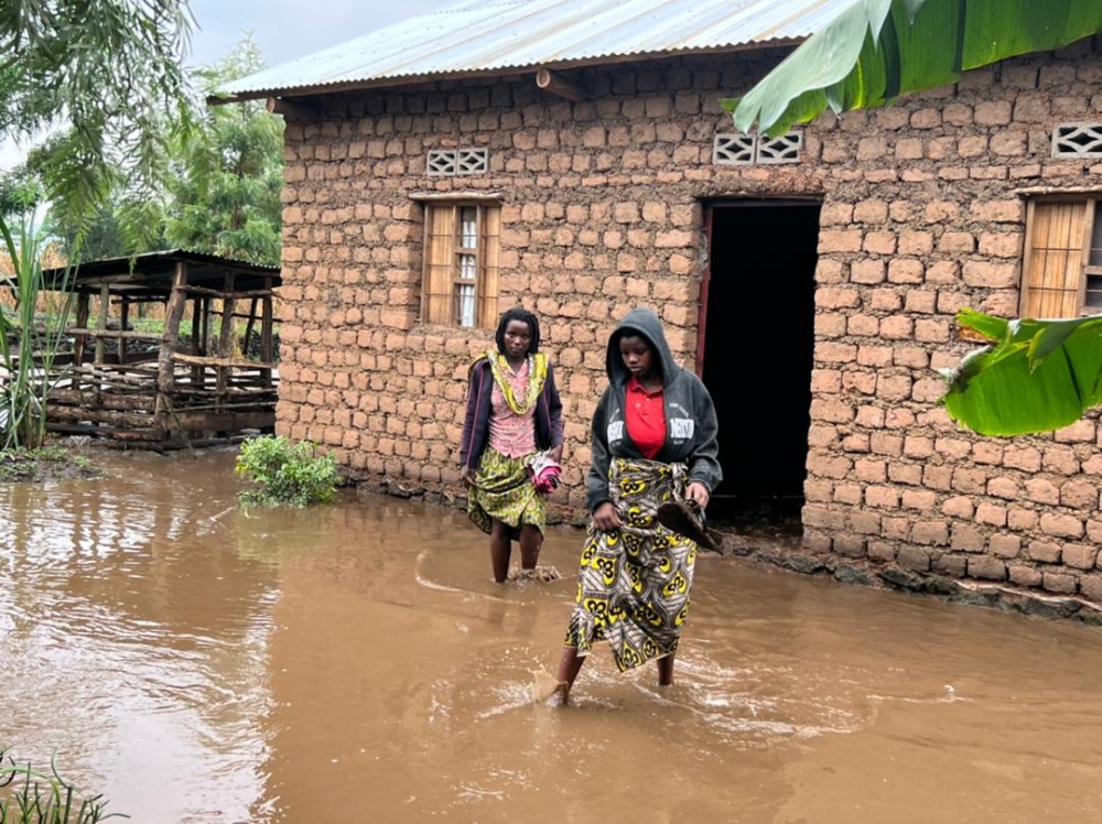 Residents wade through a flooded residental area after heavy rains that causes overflow of drainages from Volcanoes National Park, that caused damages in Musanze on June 24. Courtesy