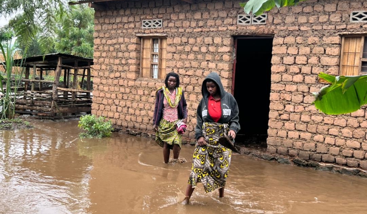 Residents wade through a flooded residental area after heavy rains that causes overflow of drainages from Volcanoes National Park, that caused damages in Musanze on June 24. Courtesy