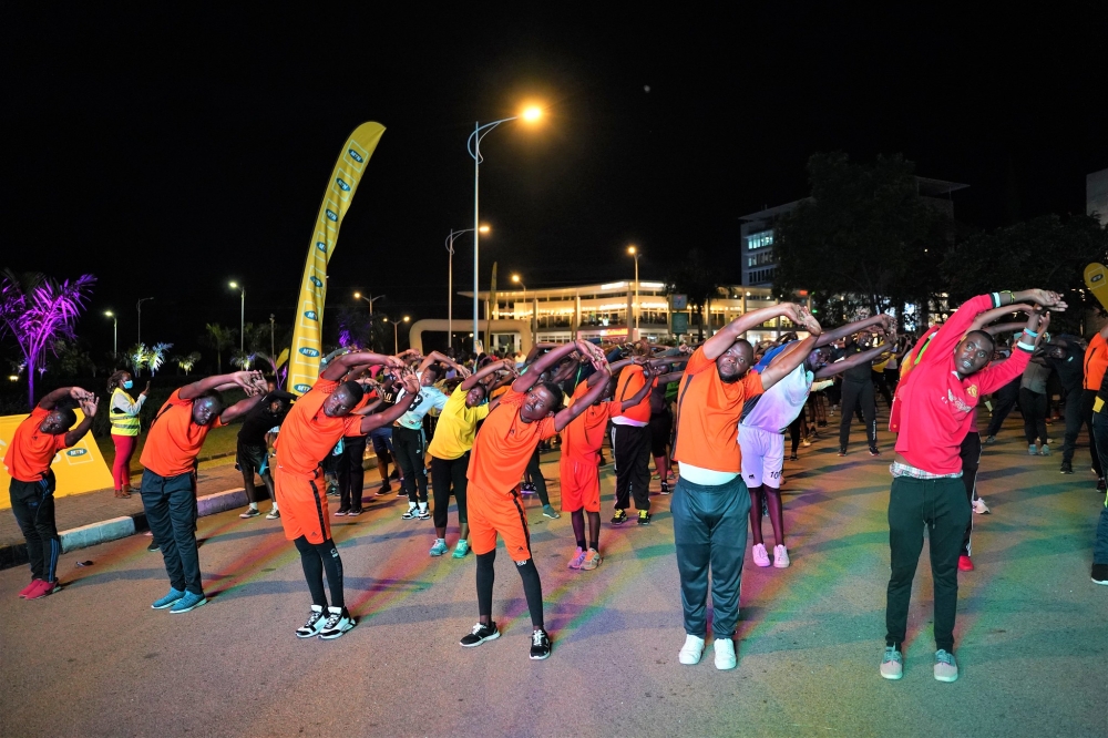 Kigali residents stretch their bodies during an evening of Kigali Night Run. Photo by Craish Bahizi