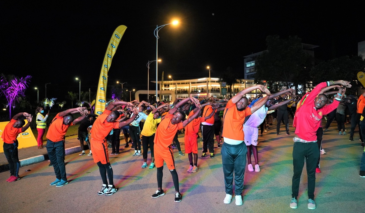 Kigali residents stretch their bodies during an evening of Kigali Night Run. Photo by Craish Bahizi
