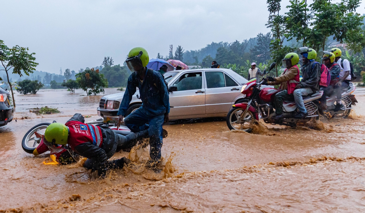 Taxi-moto operators wade through a flooded street in Kigali. FILE