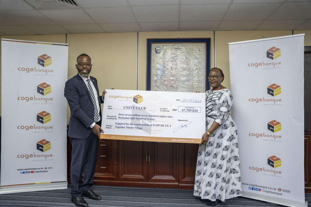 Guillaume Ngamije Habarugira, the CEO of Cogebanque hands over a cheque to Régine Iyamuremye, the Executive Secretary of Unity Club Intwararumuri  at the event on Thursday, July 27. Photos by Emmanuel Dushimimana