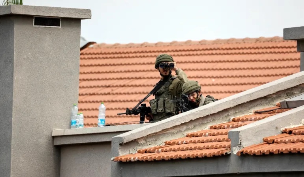 Israeli soldiers look out as they stand between buildings in Sderot, southern Israel [Amir Cohen/Reuters]