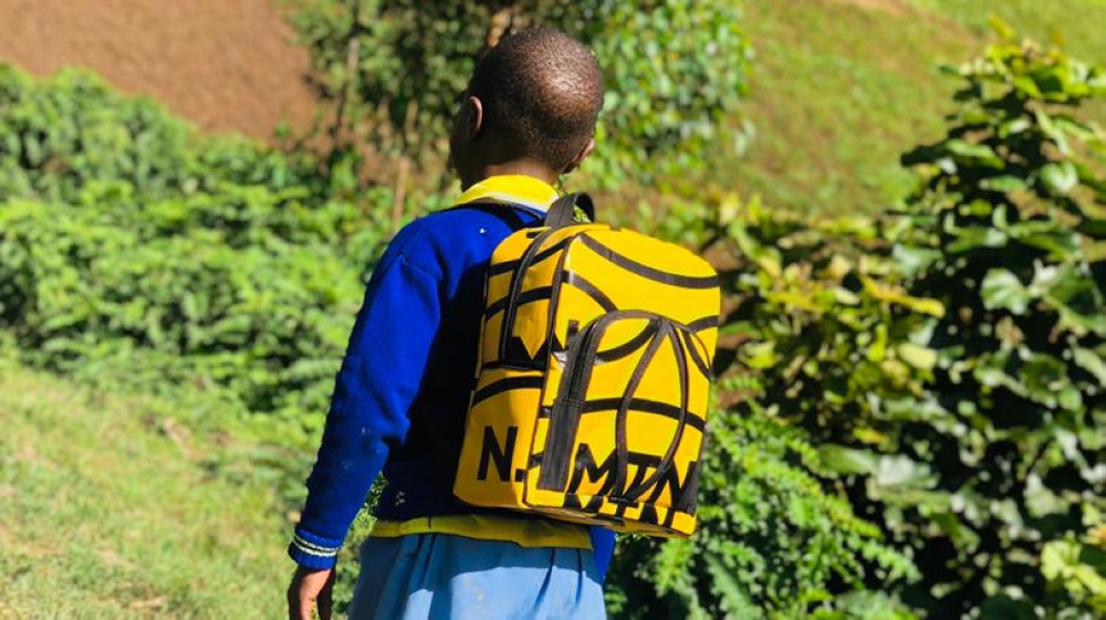 A child heading to school carrying a school bag made out a plastic banner