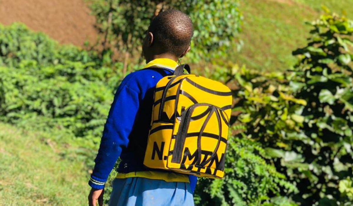A child heading to school carrying a school bag made out a plastic banner