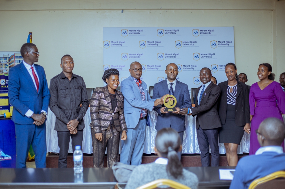 Dr. Martin Kimemia (left) assisted by Dr. John Nyiligira show off the gift given by the outgoing leaders. Looking on from the left is Mr. Robert Rukikira