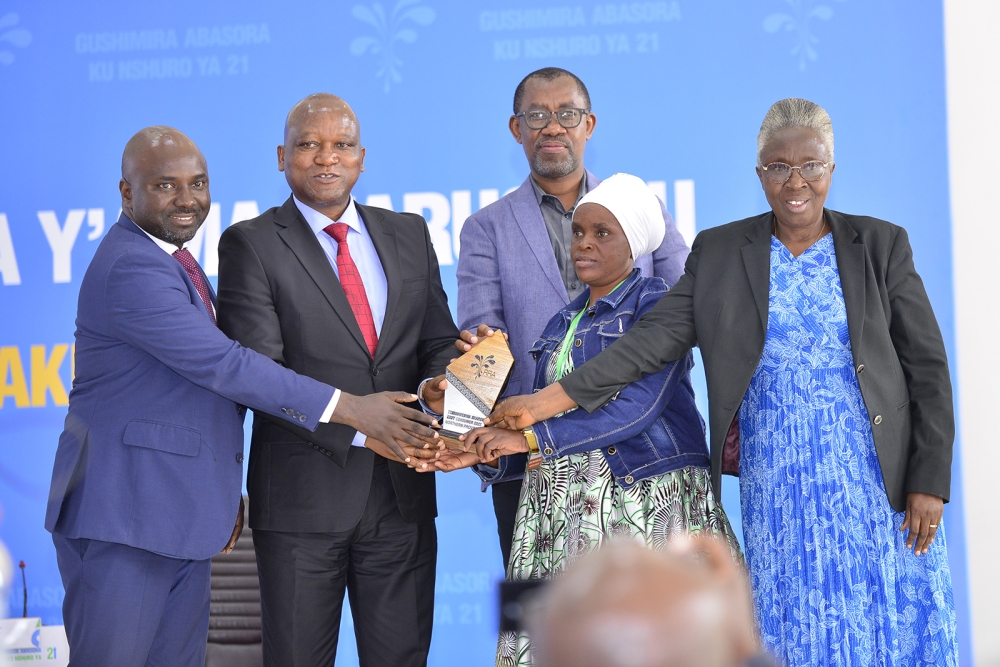 Minister of Defence Juvénal Marizamunda and RRA Boss Pascal Bizimana Ruganintwali award Sharon Tindimwebwa, the best buyer who always requests EBM invoices, at a taxpayer appreciation event in Northern Province. Courtesy