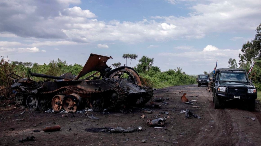 Cars passing by a destroyed military vehicle in Rugari, after clashes between the Congolese army and M23 rebels in the east of the Democratic Republic of Congo on January 6, 2023. PHOTO: AFP