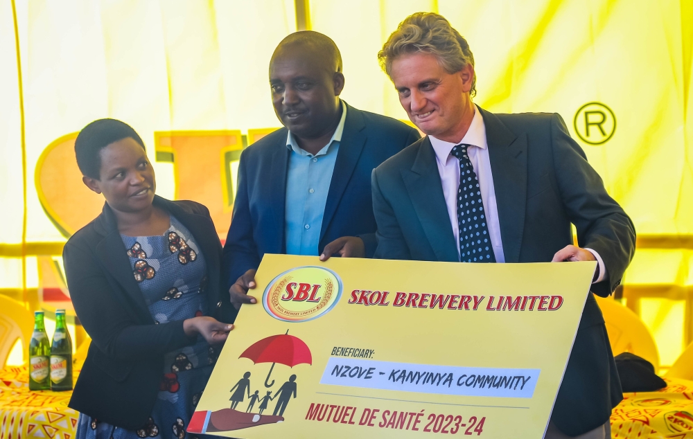 Eric Gilson, the General Manager of SKOL hands over the donation of community health insurance, Mutuelle de Santé, to 842 individuals residing in the neighbourhood of the brewery in Nzove. Dan Gatsinzi