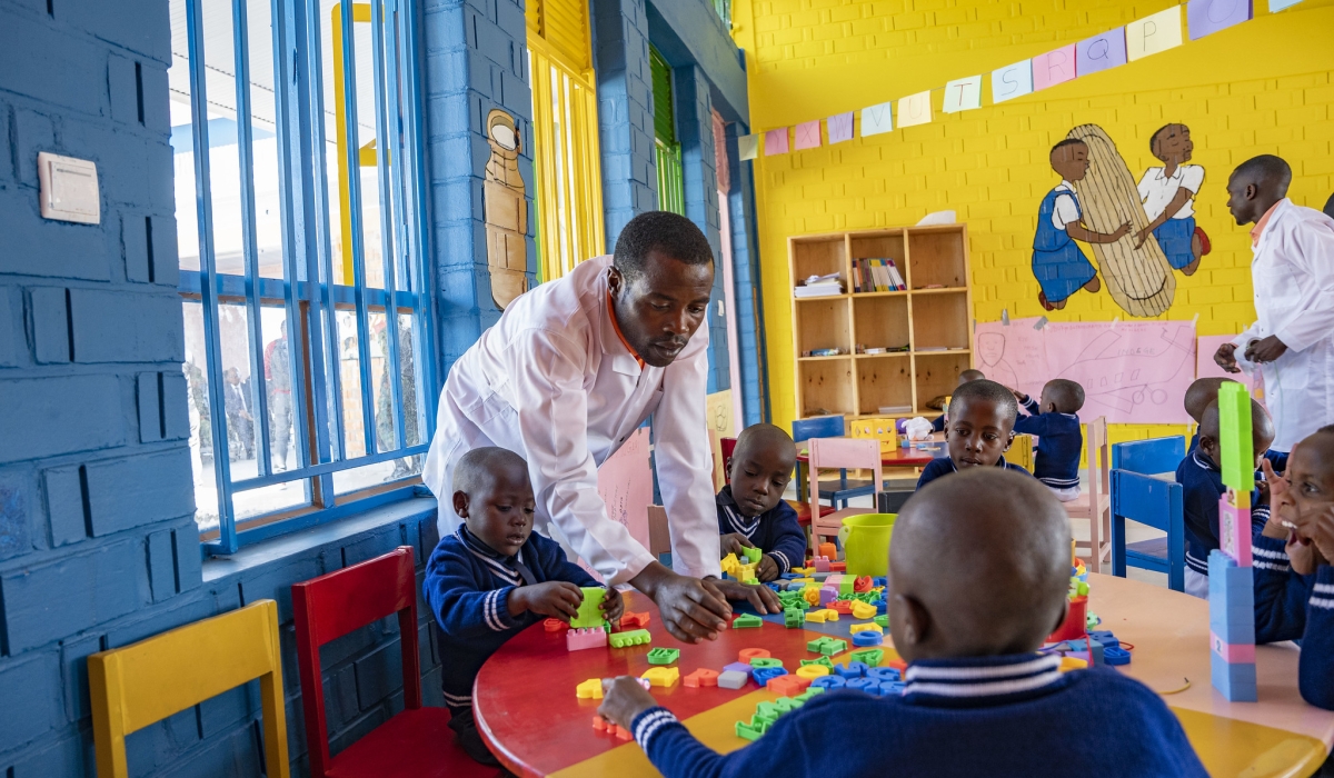 A caretaker helps children at the newly constructed early childhood development center at Rugerero Model Village. Photo by Emmanuel Dushimimana