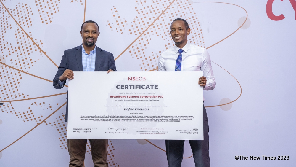 Christian Muhirwa, the CEO of Broadband Systems Corporation(Right) shows a  certificate to the audience as they celebrate ISO standards, NCSA data controller certification. Photos by Emmanuel Dushimimana