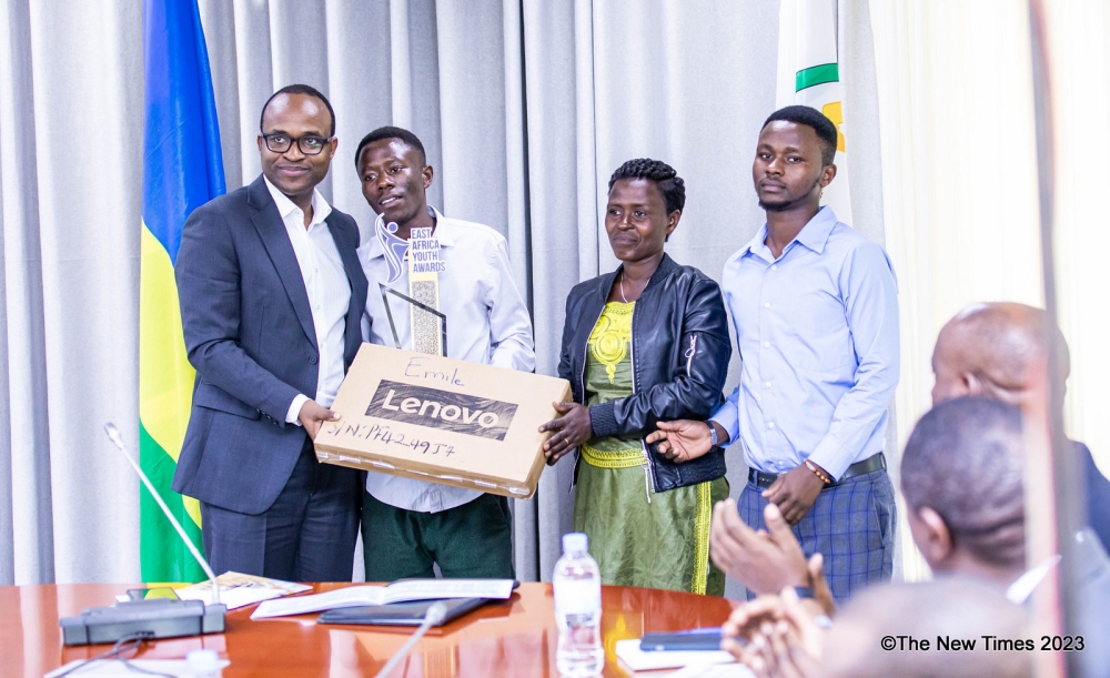 Minister of Education Gaspard Twagirayezu hands over a laptop to  the 19-year-old,  Emile Cyubahiro who is the overall winner in science during the event in Kigali on December 4. Photo by Dan Gatsinzi