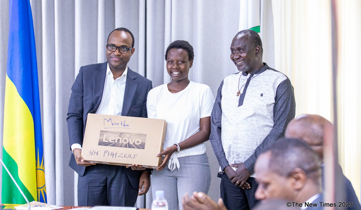 Minister of Education Gaspard Twagirayezu hands over a laptop to a  19-year-old winner Martha Izere Samaza and her father Emilien Bisamaza during the event. Photo by Dan GATSINZI