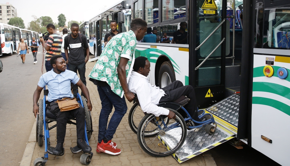 Some people with disabilities are assisted to board a bus in Kigali. Photo by Craish Bahizi