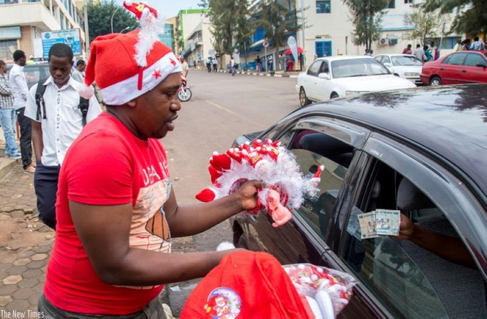 A hawker sells toys to a customer in downtown Kigali. The festive season involves celebrations that require spending money on food, gifts, or outings. File photo