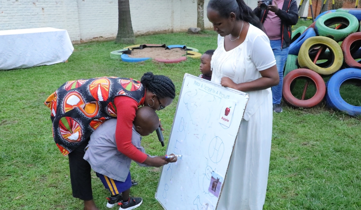 A mother helps her autistic child write on a flip chart at the Kigali Autism Centre in Kagugu, Gasabo District on December 23, 2022. Photo Craish Bahizi